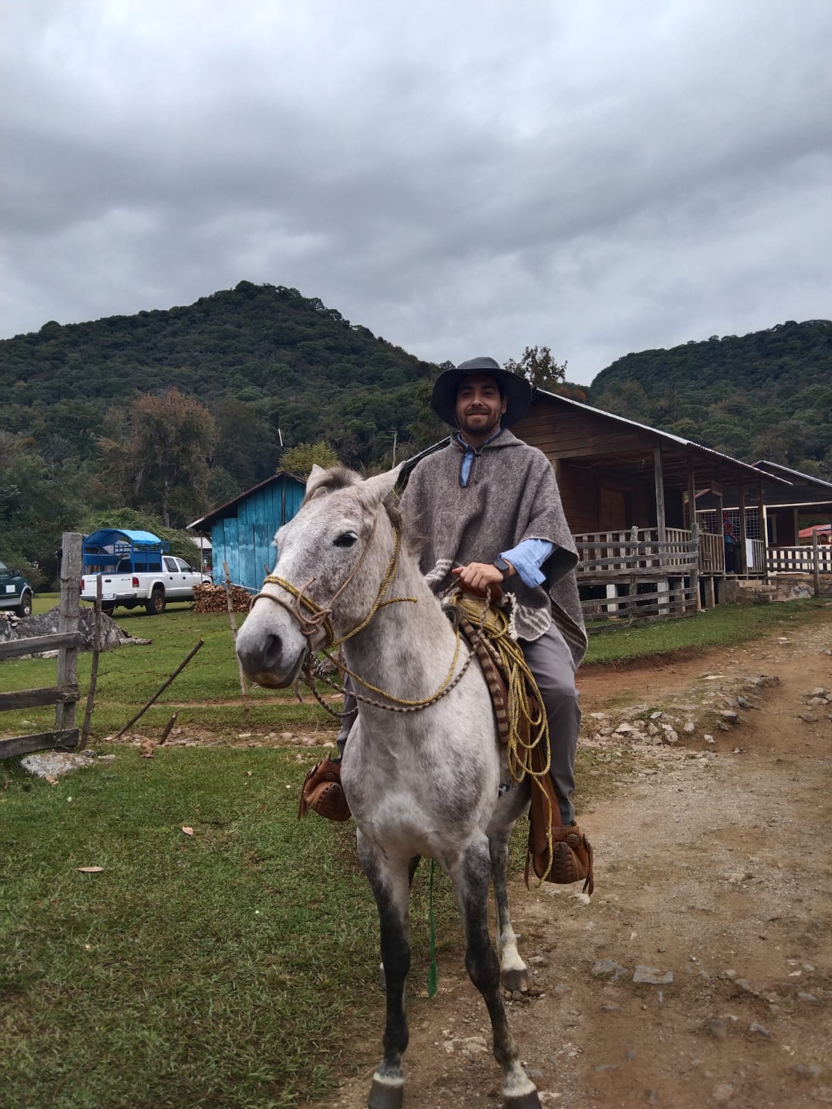 Guía local a caballo con poncho frente a las cabañas de la reserva